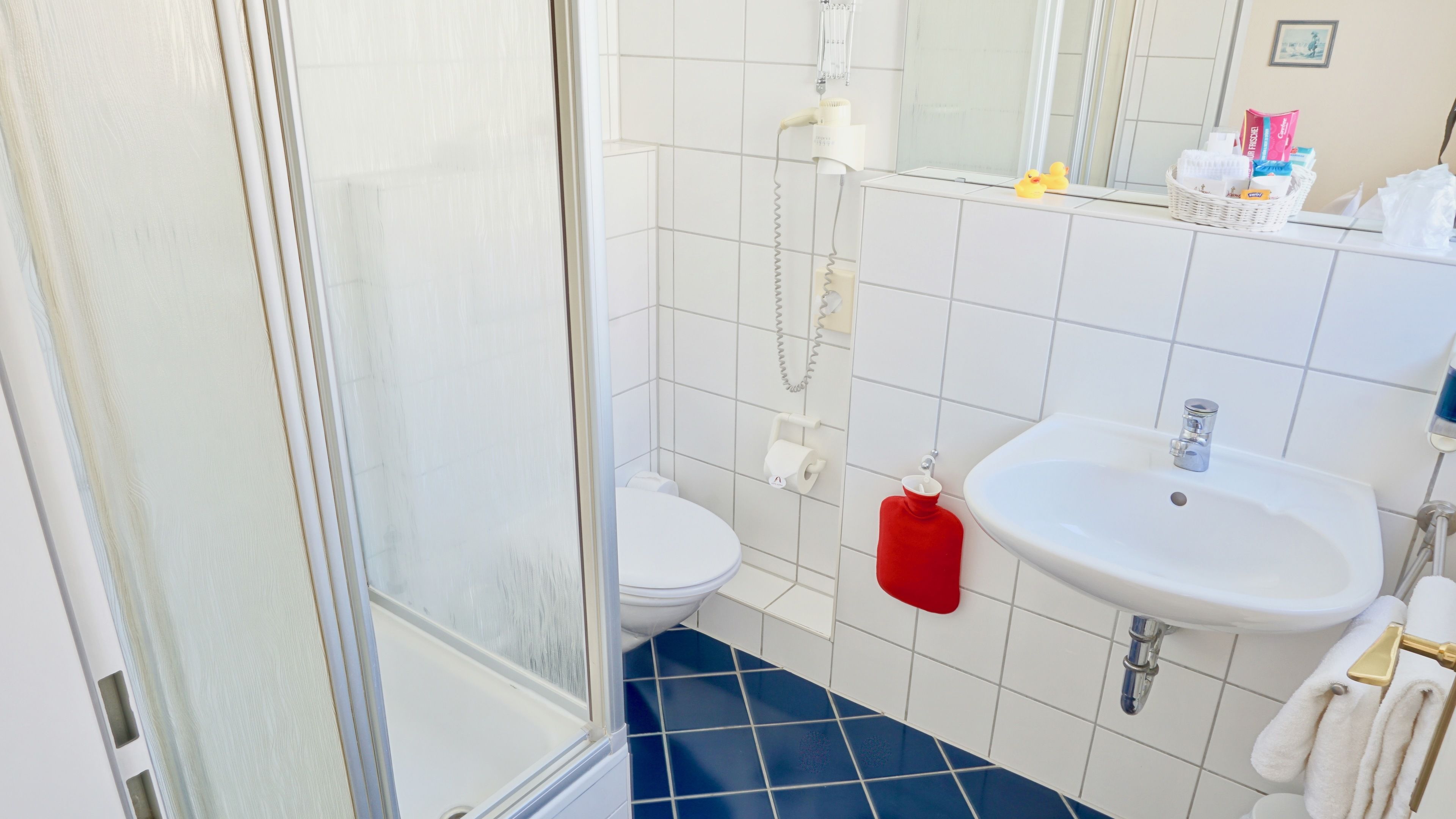 A bathroom with a white sink, a toilet, and a shower area.