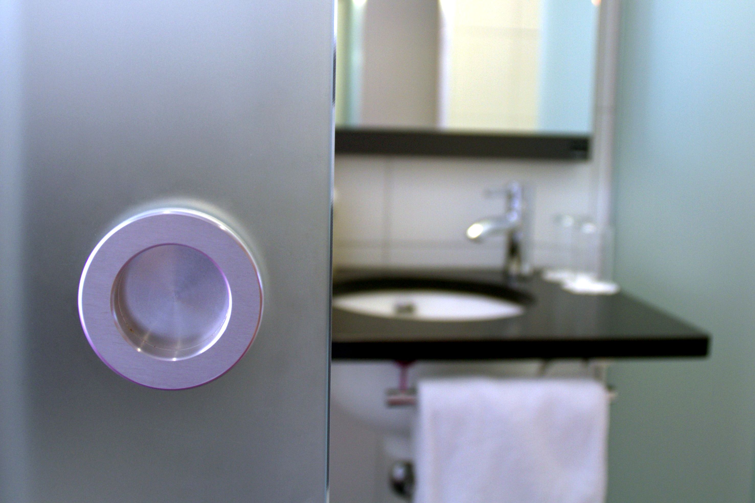 Un baño con lavamanos, espejo y toallero.