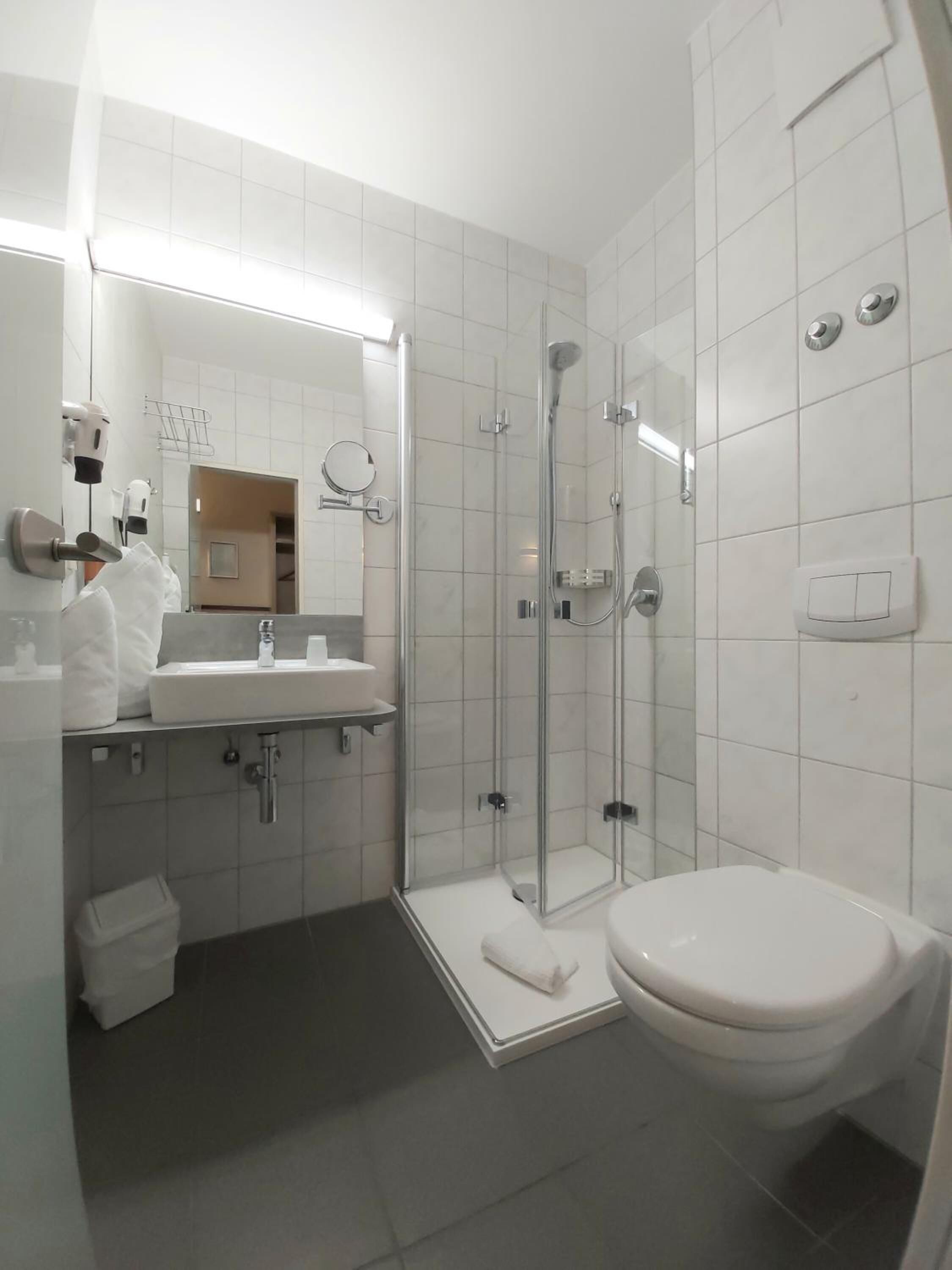 A modern bathroom with a glass-enclosed shower, a white sink, and a toilet.