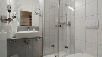 A modern bathroom with a glass-enclosed shower, a white sink, and a toilet.