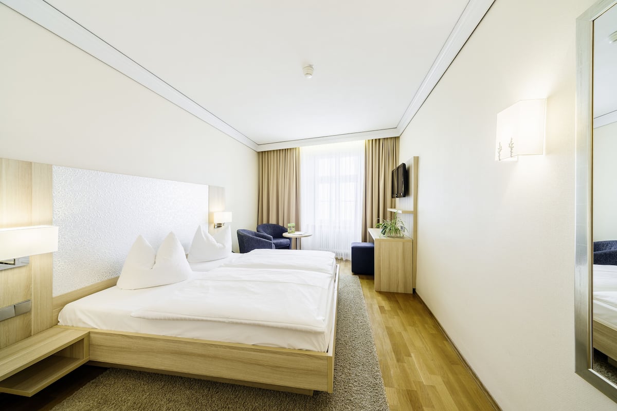 Een hotelkamer met een groot bed, nachtkastjes, een bureau, een stoel en een televisie.