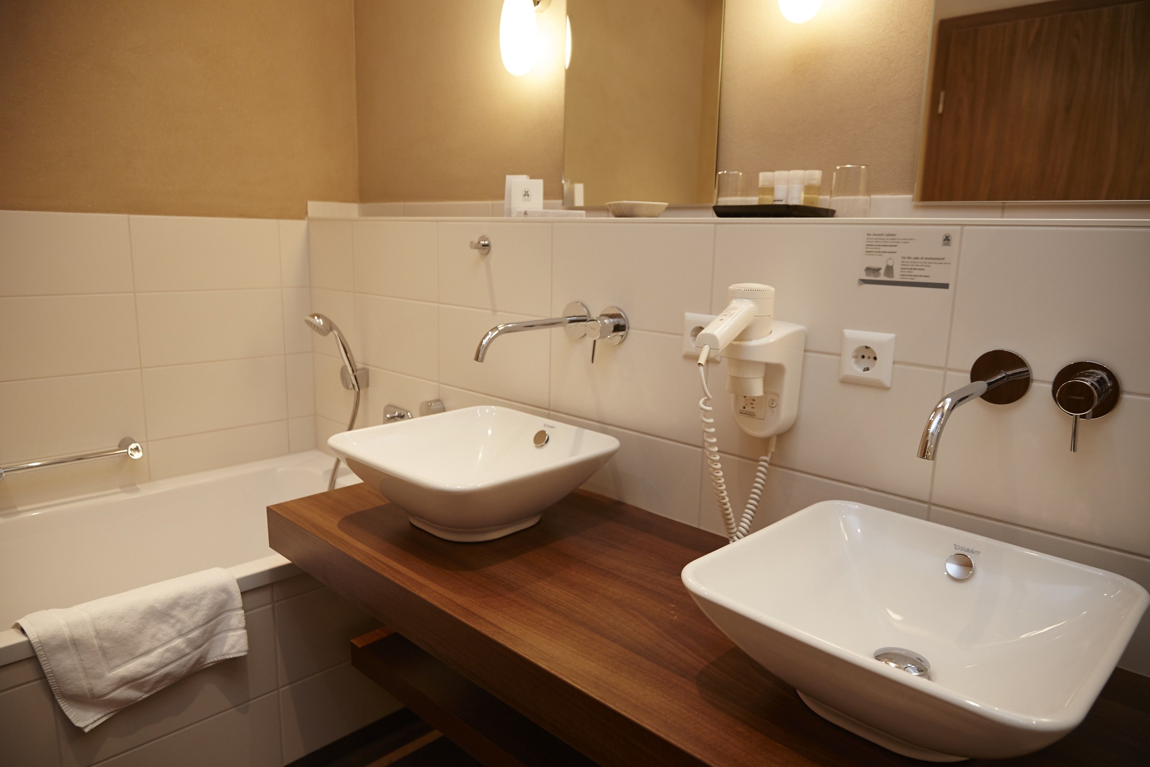 Ein Badezimmer mit zwei Waschbecken, einer Badewanne und einem Handtuchhalter.