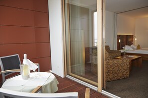 Een hotelkamer met balkon, een bank, een tafel en een bed.
