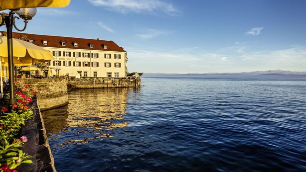 Un hôtel situé au bord de l’eau, doté d’un grand bâtiment, d’un espace extérieur aménagé et offrant une vue sur l’eau.