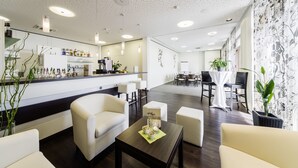 Un hall d’hôtel moderne comprenant un bar, des espaces de détente et un coin repas.