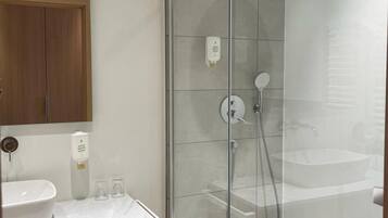 Une salle de bain moderne avec une douche à parois de verre, un lavabo blanc et un meuble-lavabo en bois.