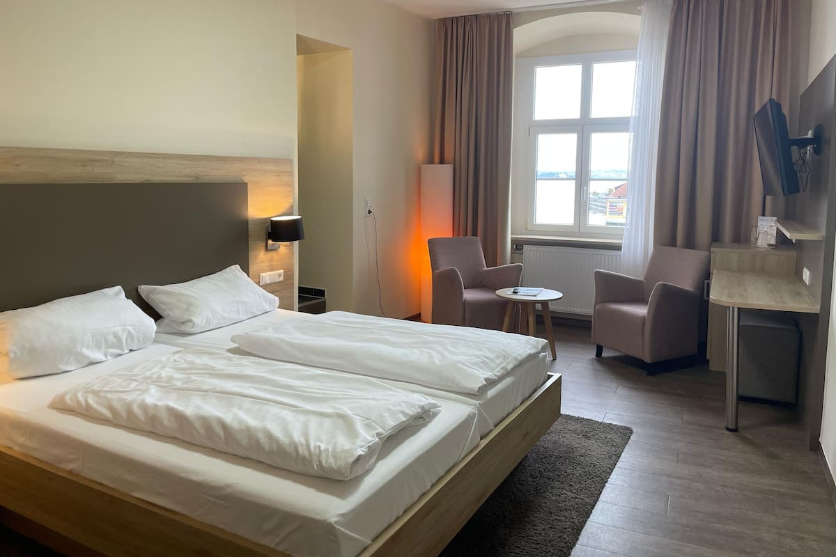 Een hotelkamer met een groot bed, twee nachtkastjes, een bureau, een stoel en een televisie.