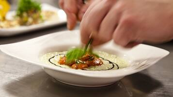 A chef preparing a dish with a white plate and a spoon.