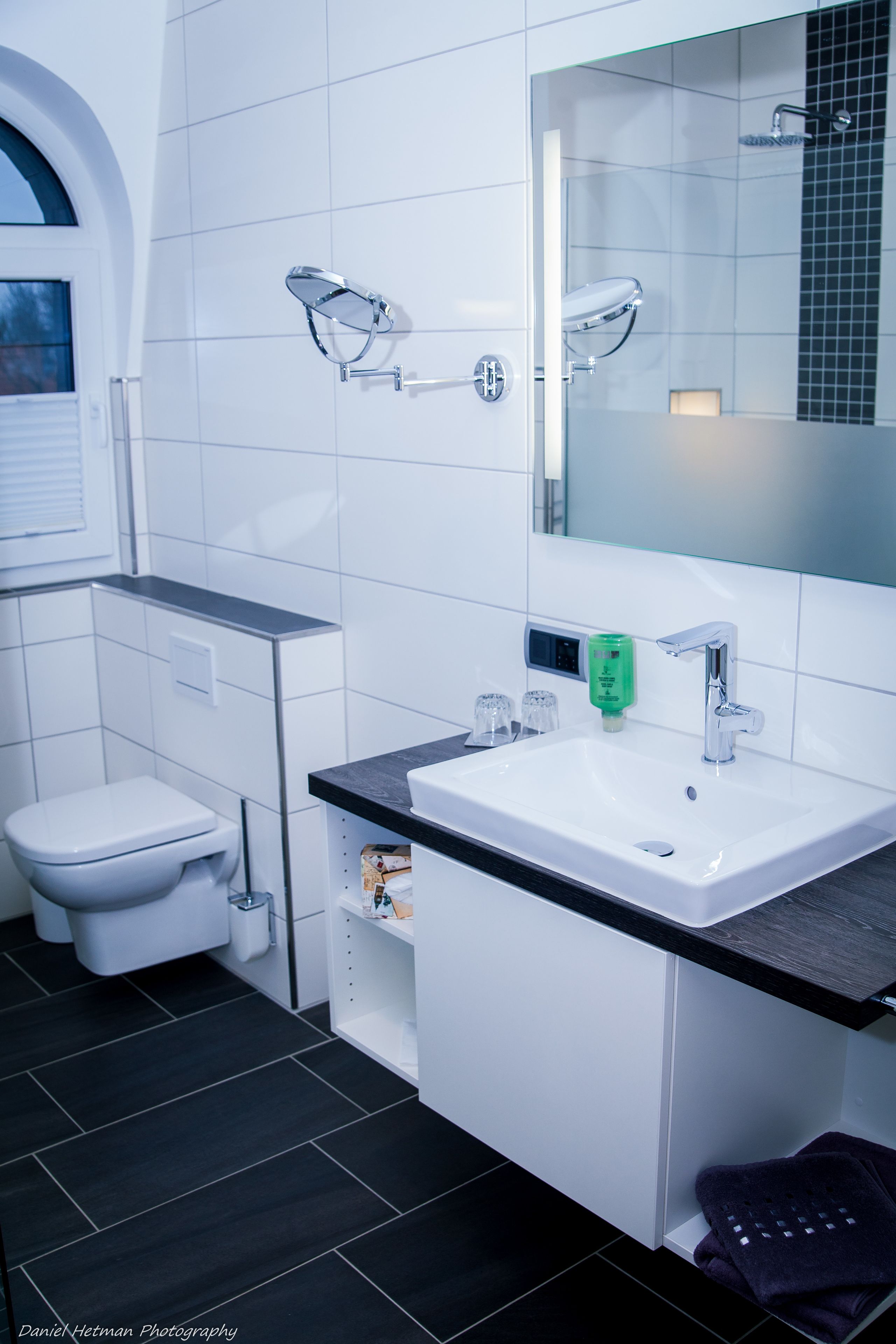 A modern bathroom with a white sink, a mirror, and a toilet.