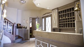 Un vestíbulo de hotel con una recepción, una escalera y vistas al comedor.