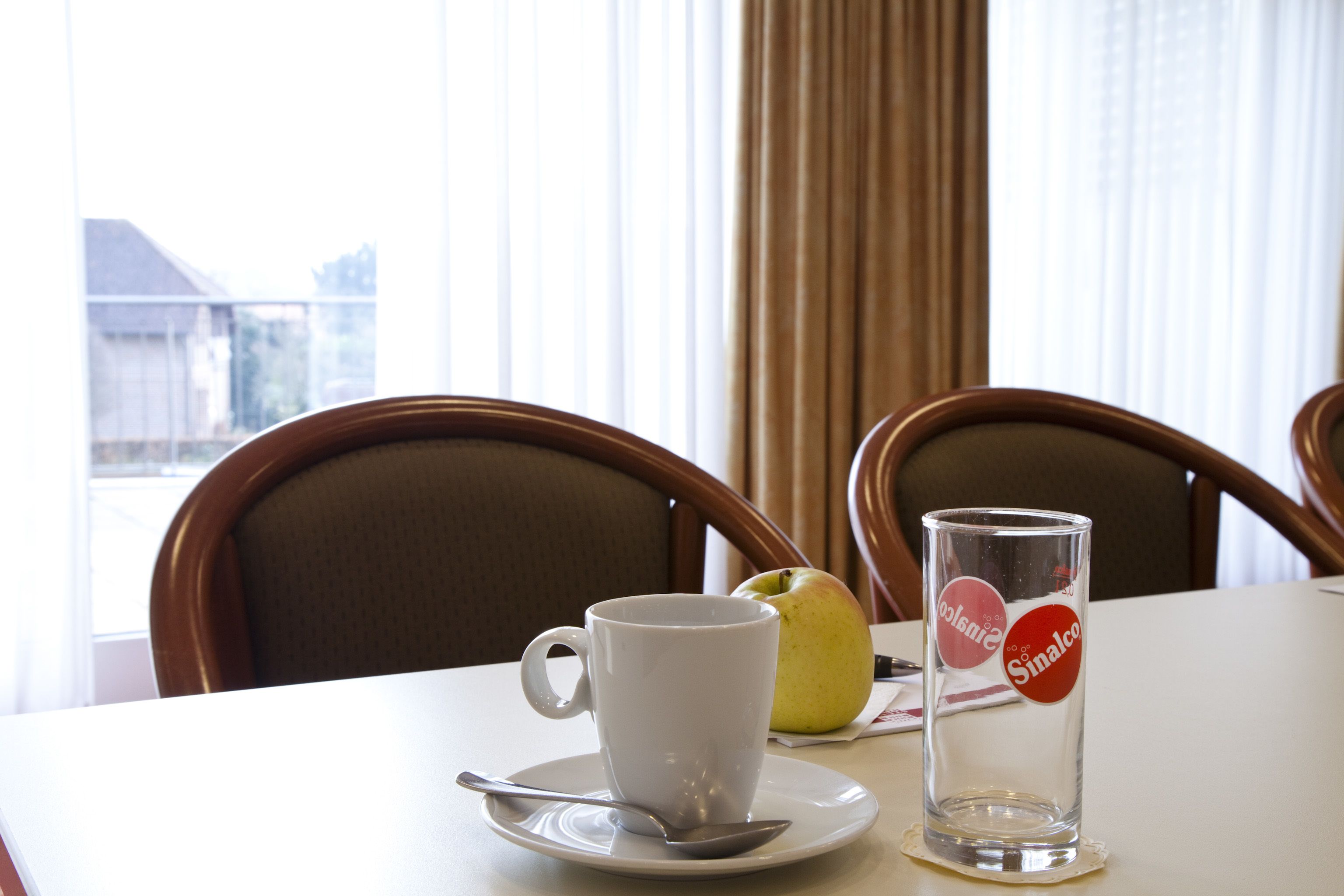 Una mesa con una taza blanca, un vaso y un limón sobre una mesa de hotel.