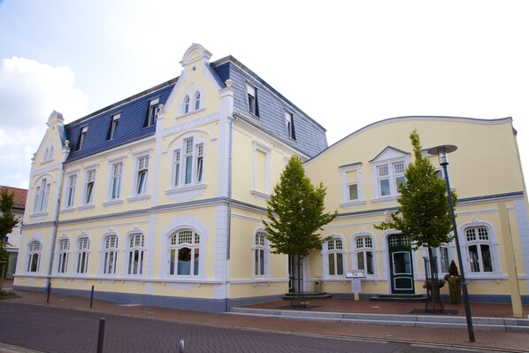 En historisk bygning med gul facade, mange vinduer og blå tag.
