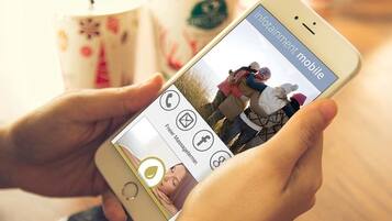 Una persona sosteniendo un teléfono inteligente que muestra una foto de dos personas en un campo.