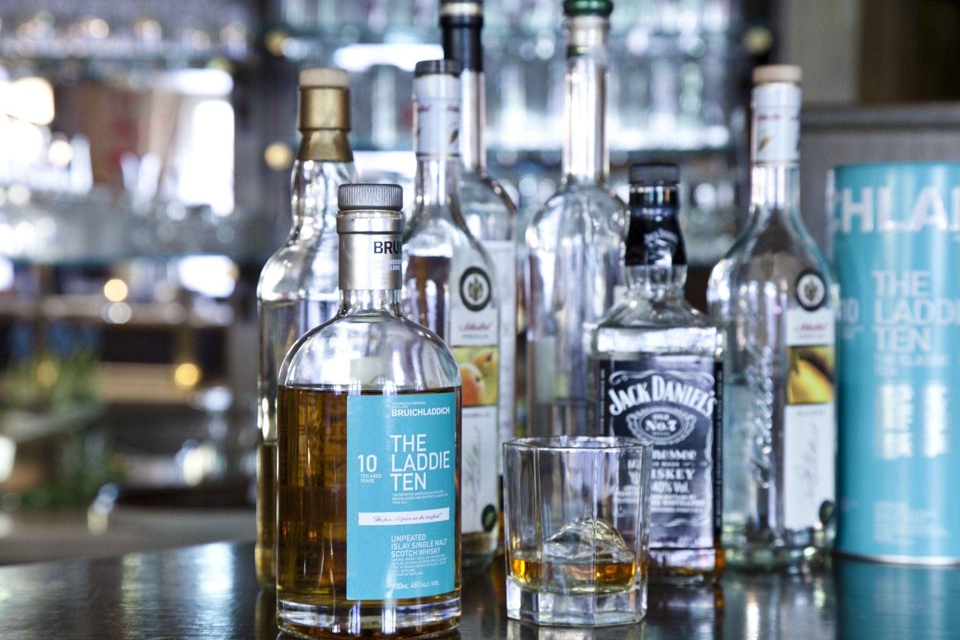 A bar with various bottles of alcohol, including a prominent bottle of The Laddie Ten whisky.