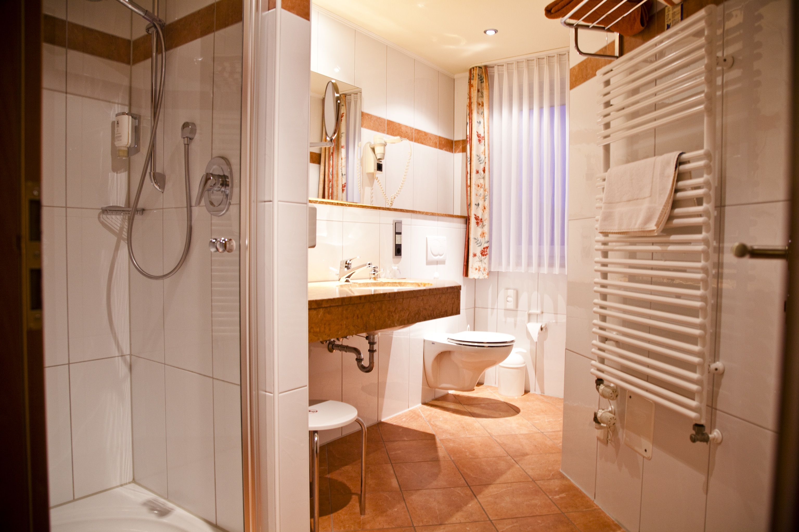 A modern bathroom with a shower, toilet, sink, and towel rack.