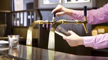 A person pouring beer from a tap into a glass on a bar counter.