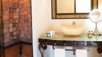A bathroom with a tiled shower, a sink with a mirror, and a towel rack.