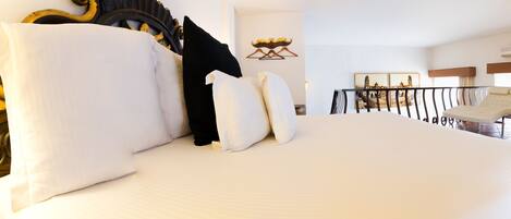 A hotel room with a large bed, a black headboard, and a view of the city through the window.