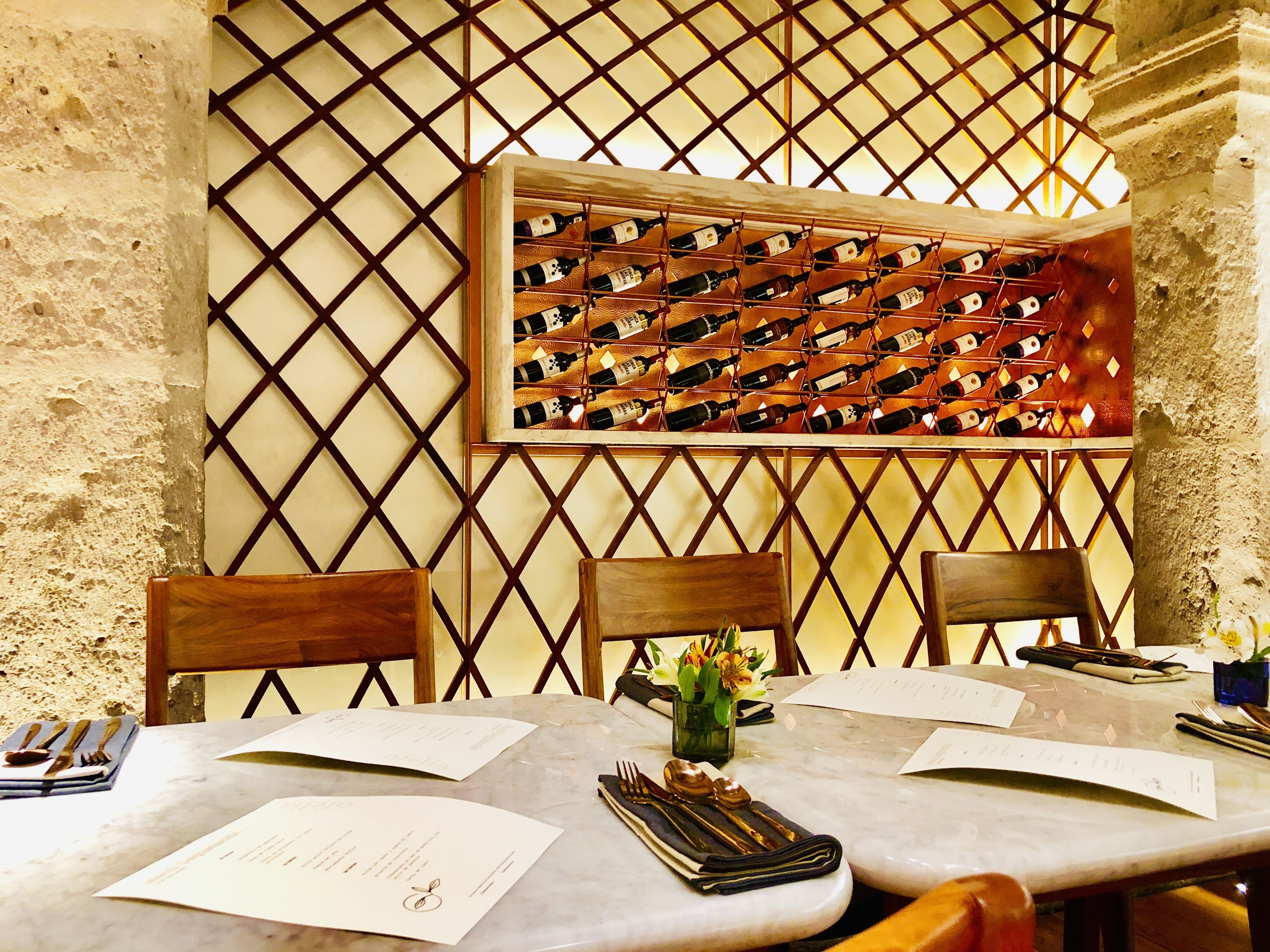 A dining table with a wine rack, two wooden chairs, and a vase with flowers.
