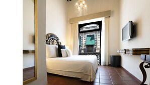 A bedroom with a bed, a mirror, a television, and a view of a balcony with a railing and a window. - HERENCIA By Hosting House (Morelia)