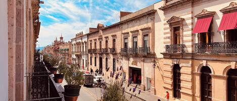 A street view with historic buildings, balconies, and pedestrians.