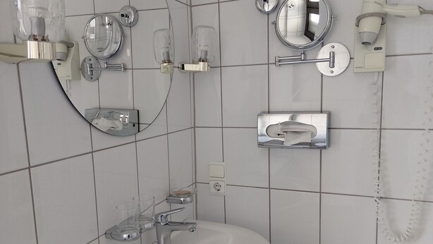 Une salle de bain avec un lavabo blanc, un miroir et deux luminaires.