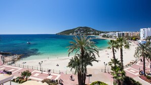 A coastal beach scene with a clear view of the sea, a sandy beach, and a hill in the background. - Bahia (Santa Eulalia del Rio)