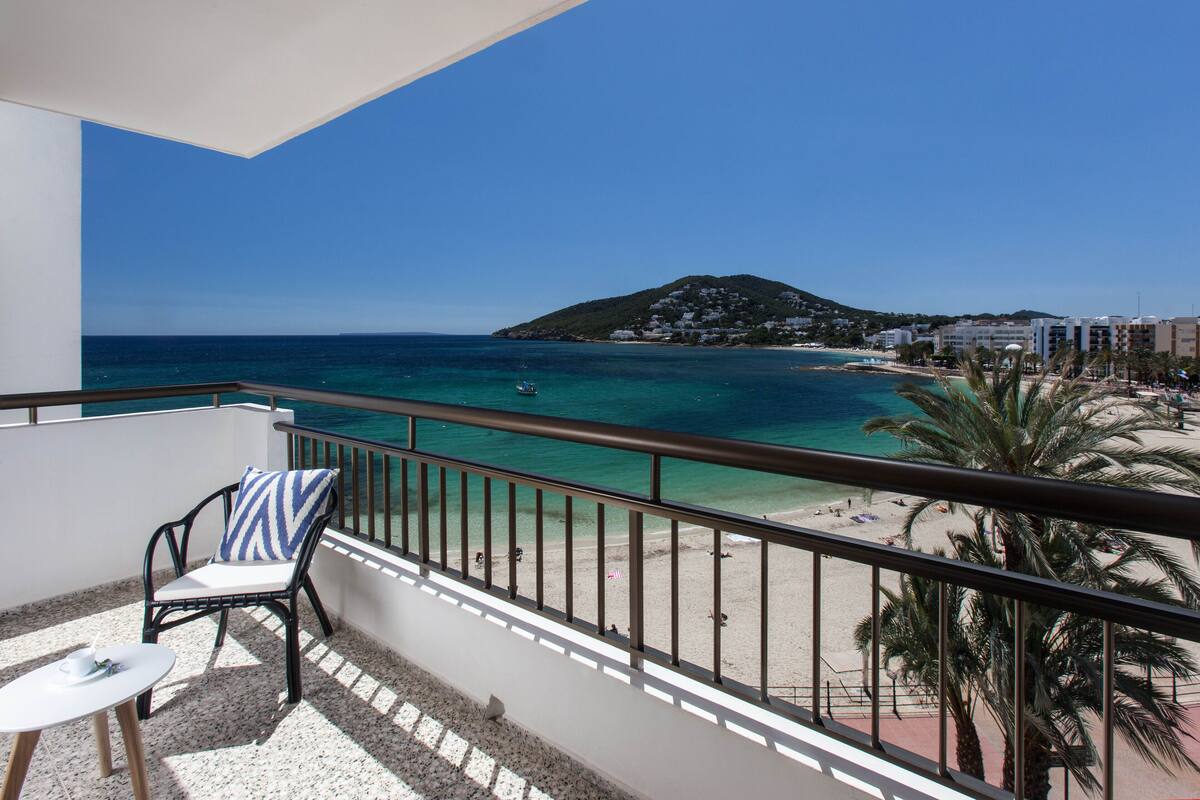 A balcony with a view of a beach and a mountain.