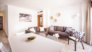 A modern living room with a white dining table, two sofas, and a small side table. - Bahia (Santa Eulalia del Rio)