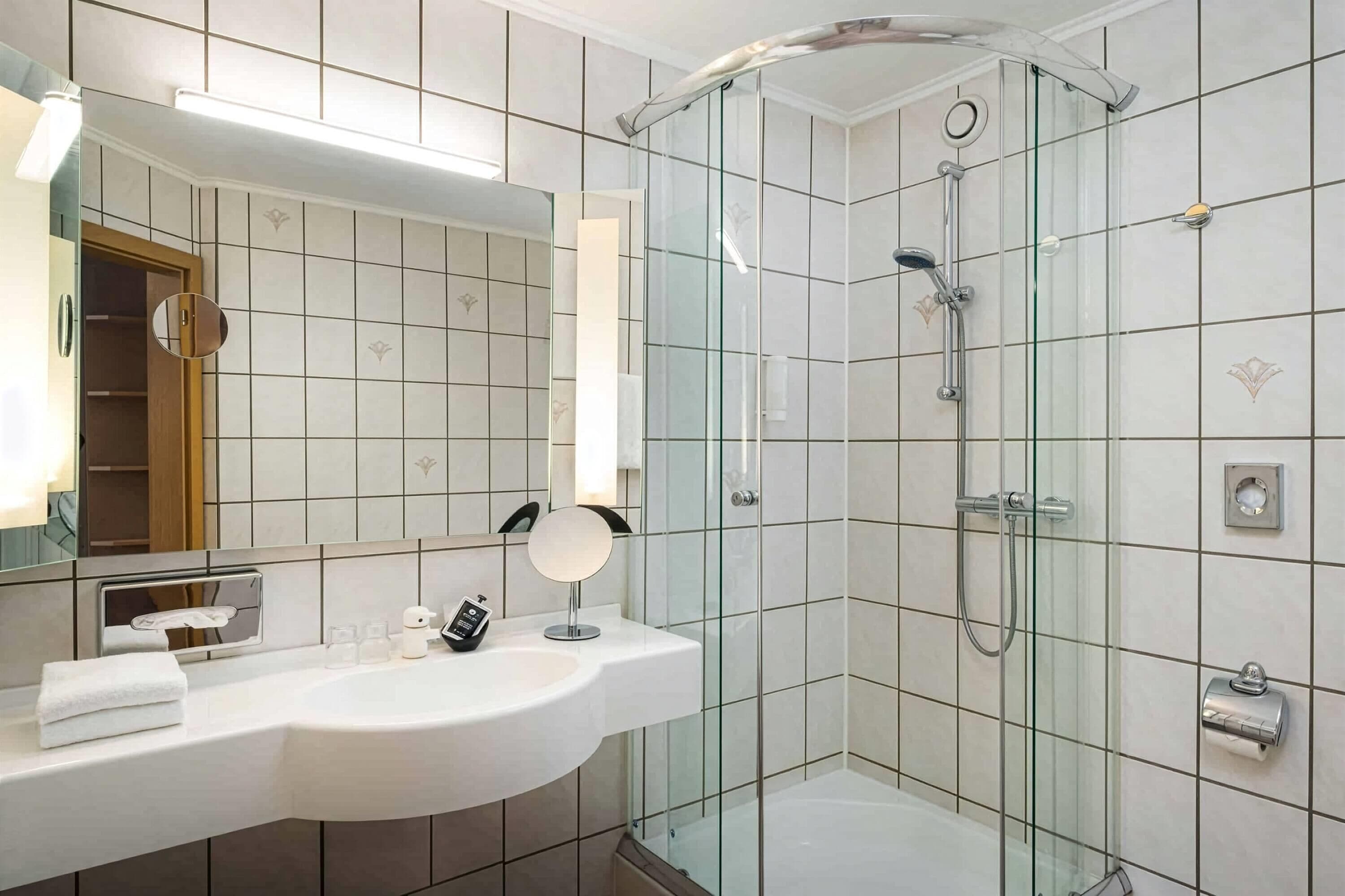 A modern bathroom with a glass shower enclosure, a vanity with a mirror, and a toilet.