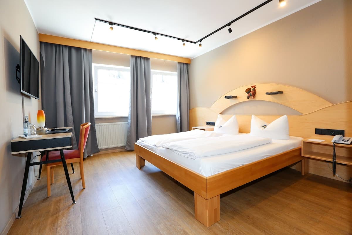 Ein modernes Hotelzimmer mit einem großen Bett, einem Schreibtisch mit Stuhl, einem Fernseher und einem Telefon.
