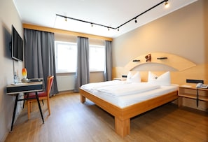 A modern hotel room with a large bed, a desk with a chair, a television, and a telephone. - Arthotel ANA Goggl, Trademark Collection by Wyndham (Landsberg am Lech)