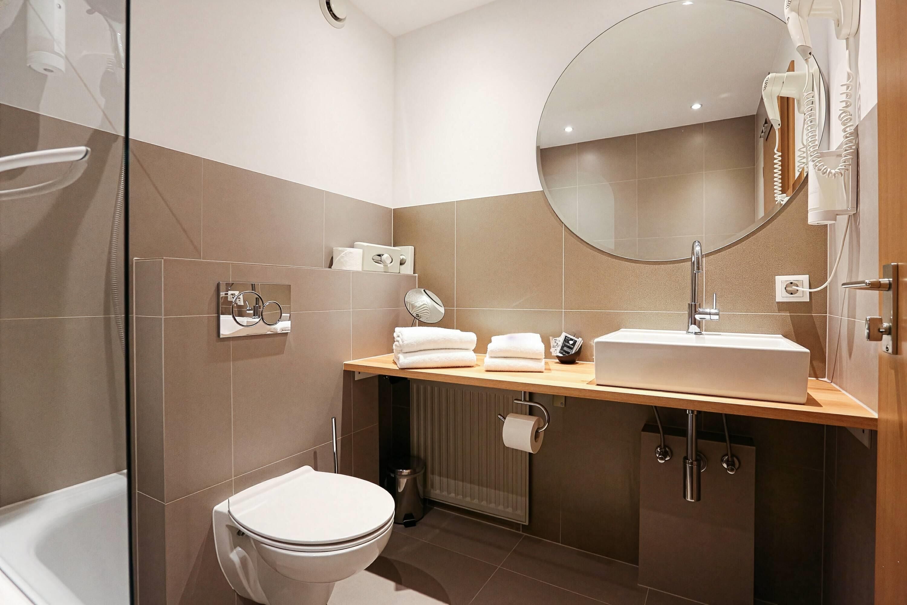 Ein modernes Badezimmer mit Toilette, Waschbecken und Dusche.