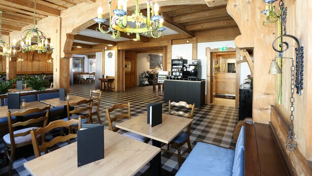 A restaurant with wooden interiors, checkered flooring, and multiple dining tables and chairs. - Arthotel ANA Goggl, Trademark Collection by Wyndham (Landsberg am Lech)