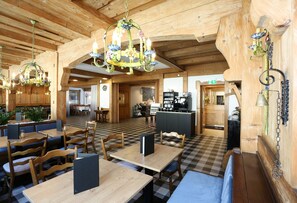 Un restaurant au décor intérieur en bois, avec un sol à carreaux et de nombreuses tables et chaises.