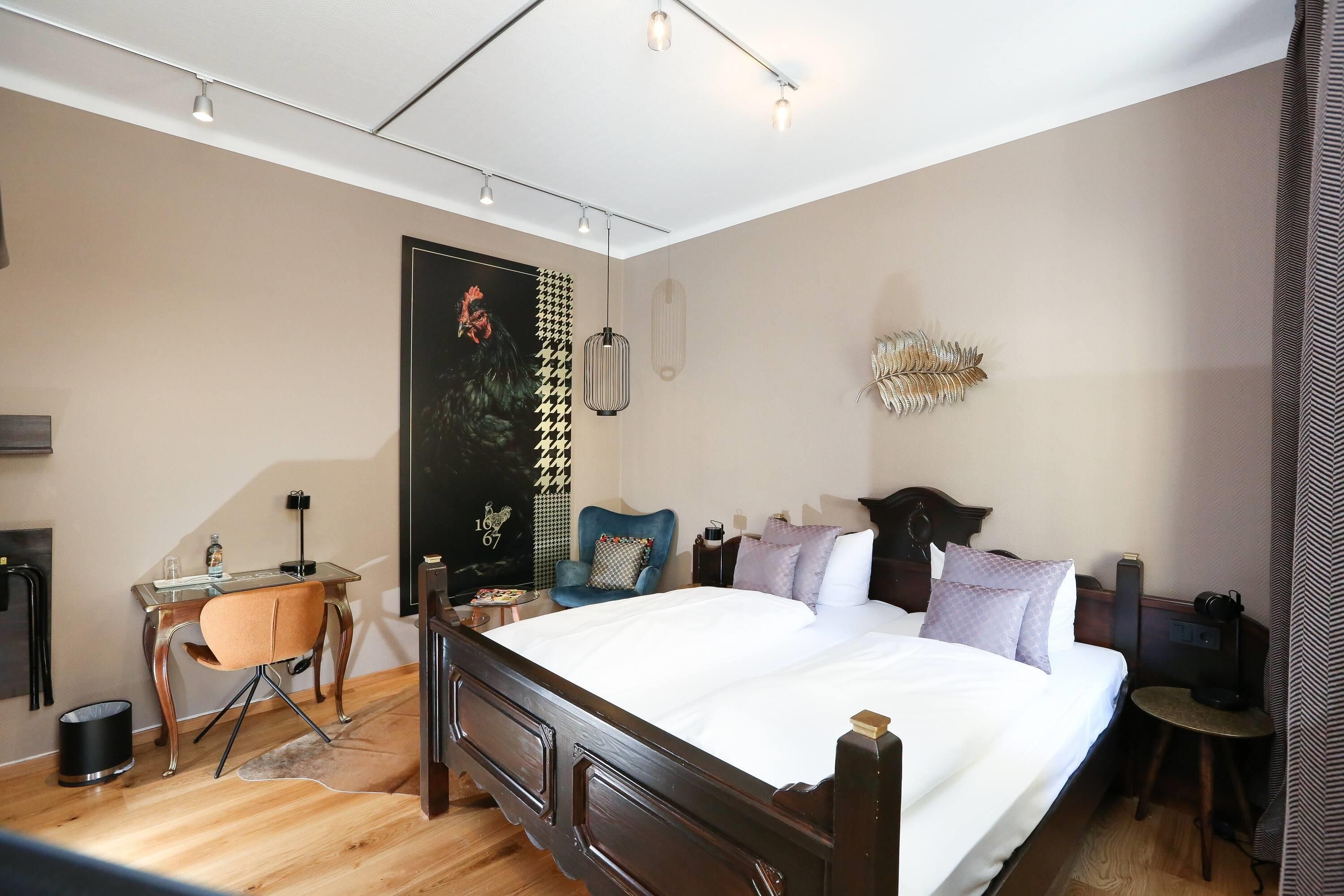 Habitació d'hotel amb un llit gran, escriptori, cadira, armari i una decoració mural.