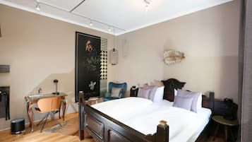 Habitació d'hotel amb un llit gran, escriptori, cadira, armari i una decoració mural.