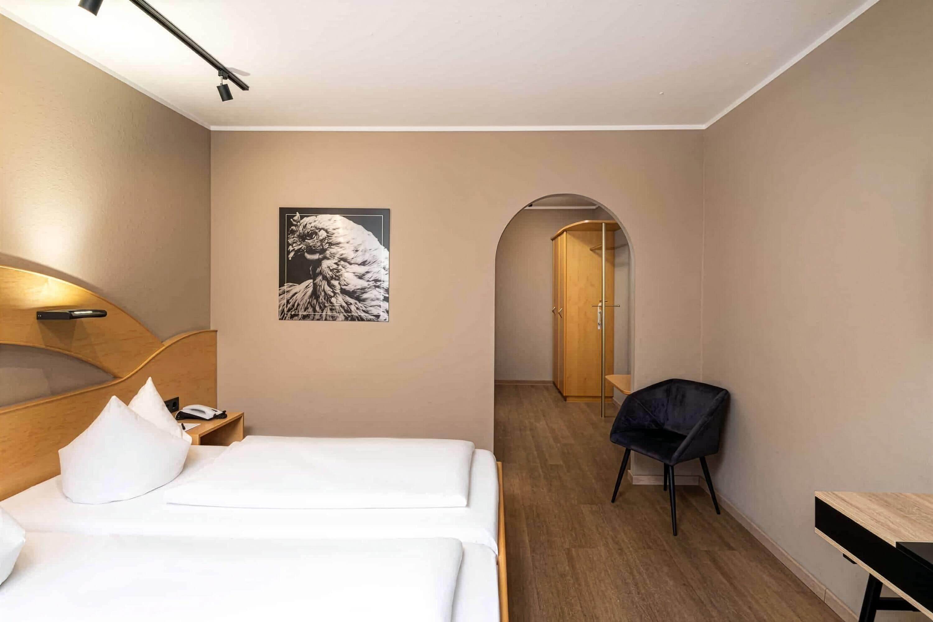 A hotel room with a bed, a desk, a chair, and a picture on the wall.