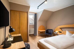 Una habitación de hotel con cama, escritorio, silla y armario.