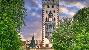 A historic building with a clock tower, an archway entrance, and a courtyard surrounded by trees. - Arthotel ANA Goggl, Trademark Collection by Wyndham (Landsberg am Lech)
