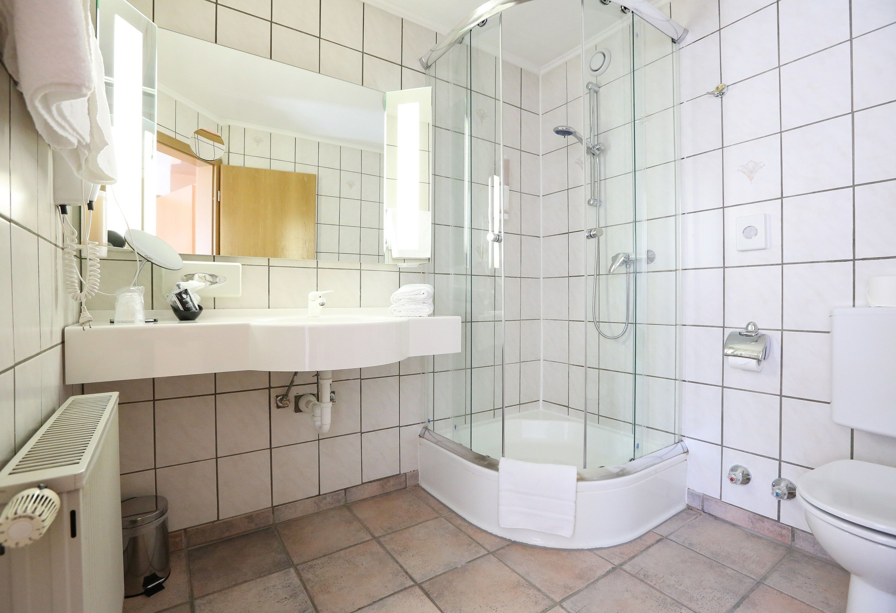 A modern bathroom with a glass-enclosed shower, a white sink, and a toilet.