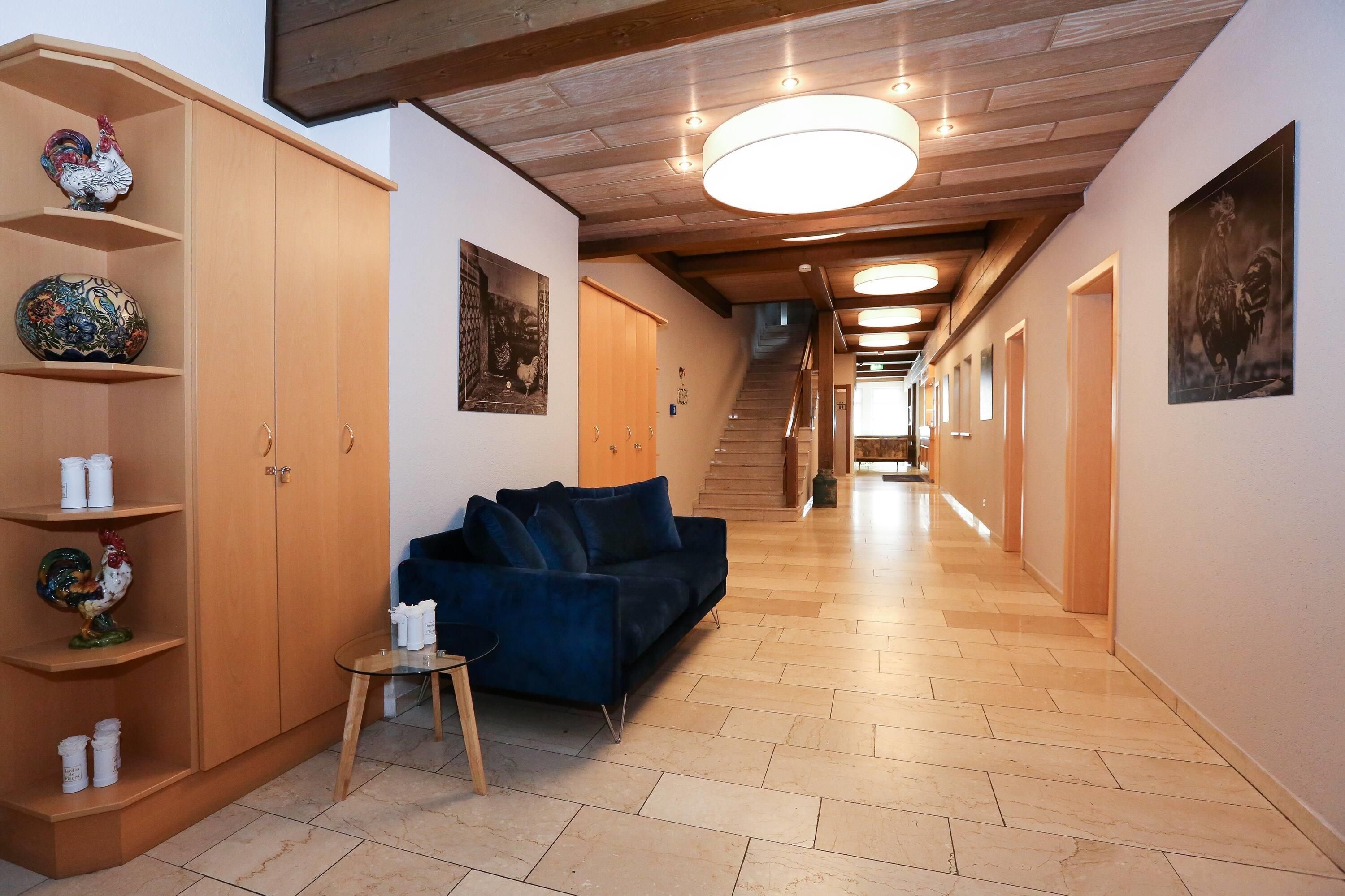 A hallway with a wooden ceiling, a blue sofa, and a wooden cabinet with decorative items.