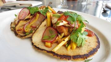 A plate of food with grilled chicken, vegetables, and herbs.