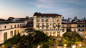 Un hotel de varios pisos con un patio central, balcones y vistas al horizonte de la ciudad.