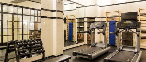 A gym with treadmills, a bench, and a rack of dumbbells.
