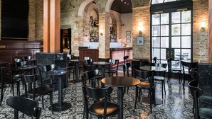 Un restaurante con paredes de ladrillo, ventanas arqueadas y diferentes opciones de asientos, incluyendo mesas y sillas.
