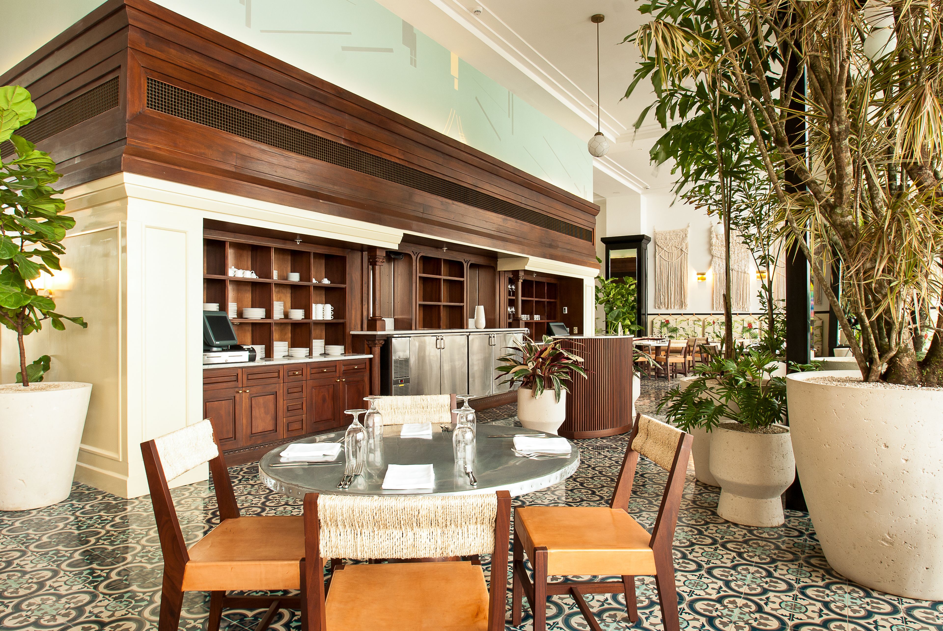A dining area with a round table, chairs, and a large potted plant.