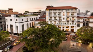 Un edificio de varios pisos con un patio central, rodeado de árboles y una estatua.