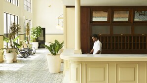 Un hall espacioso con piso de baldosas, ventanas amplias y plantas en macetas.