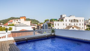 Una piscina en la azotea con cubierta de madera, rodeada de edificios con diversos estilos arquitectónicos.